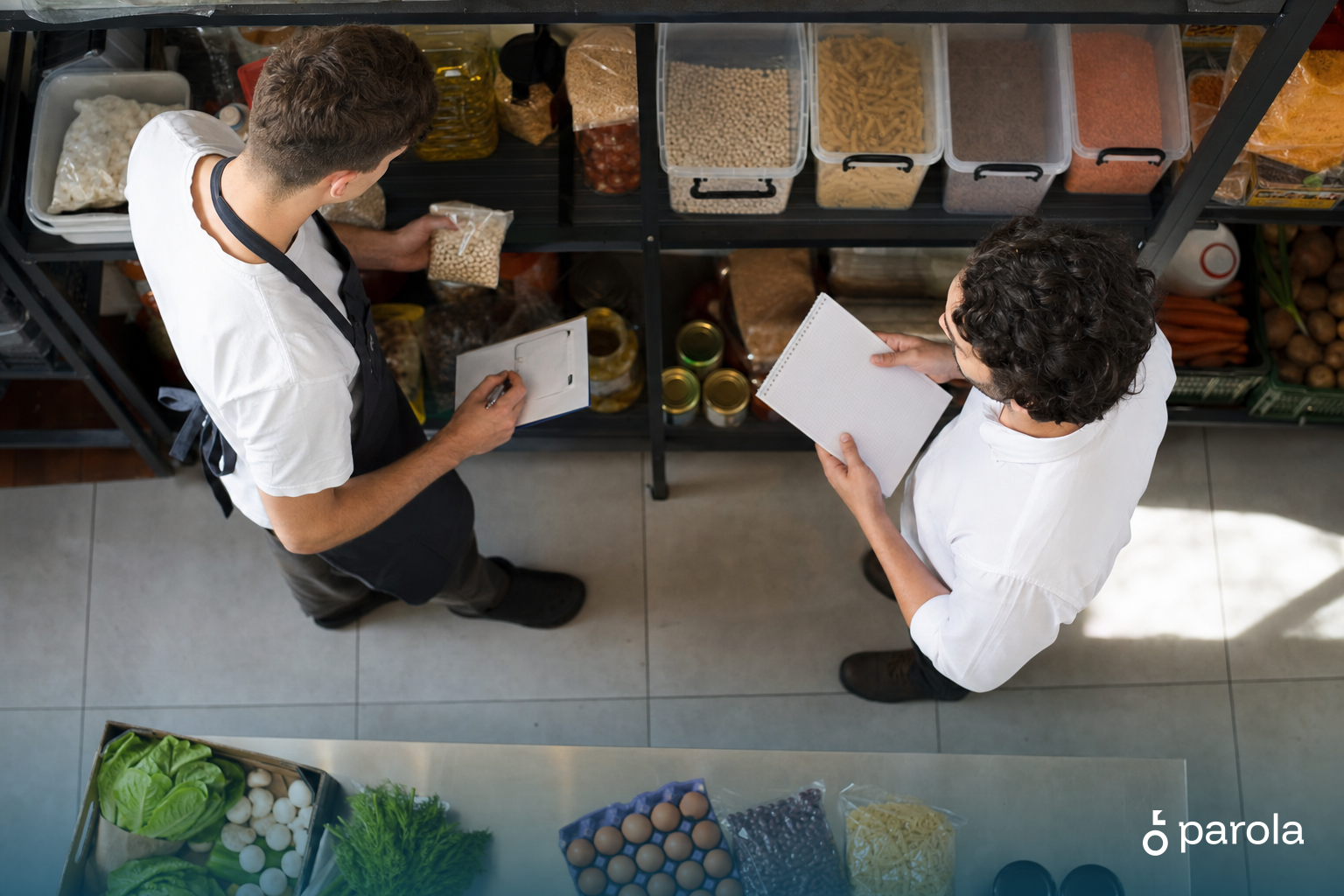 Sayım yapan çalışan ile raflardaki ürün miktarını karşılaştıran restoran yöneticisi mutfak deposunda